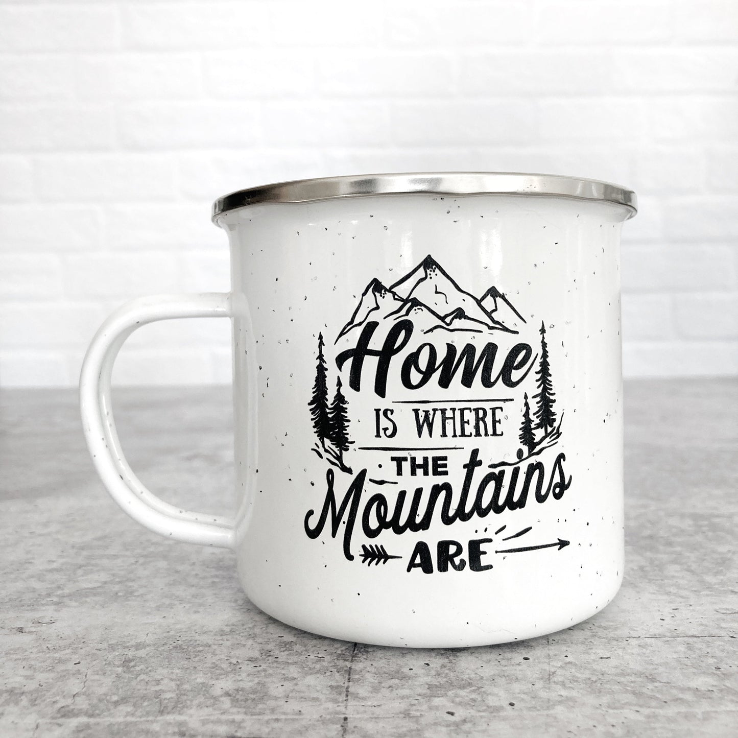 Home Is Where the Mountains Are design on a white enamel mug