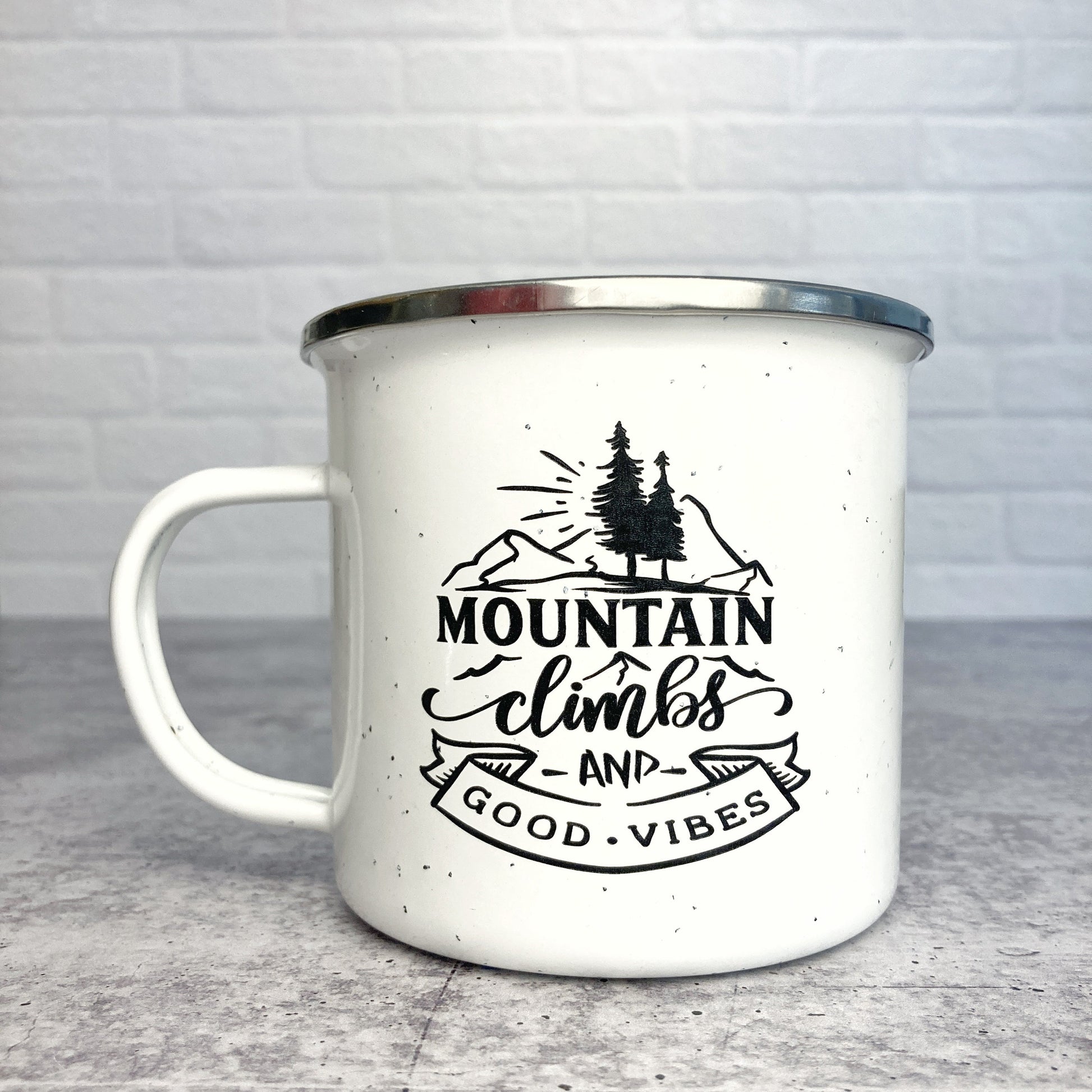 Mountain Climbs and Good Vibes design on a white enamel mug